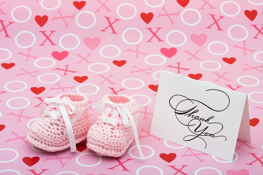 Pink booties and thank you card against pink backdrop