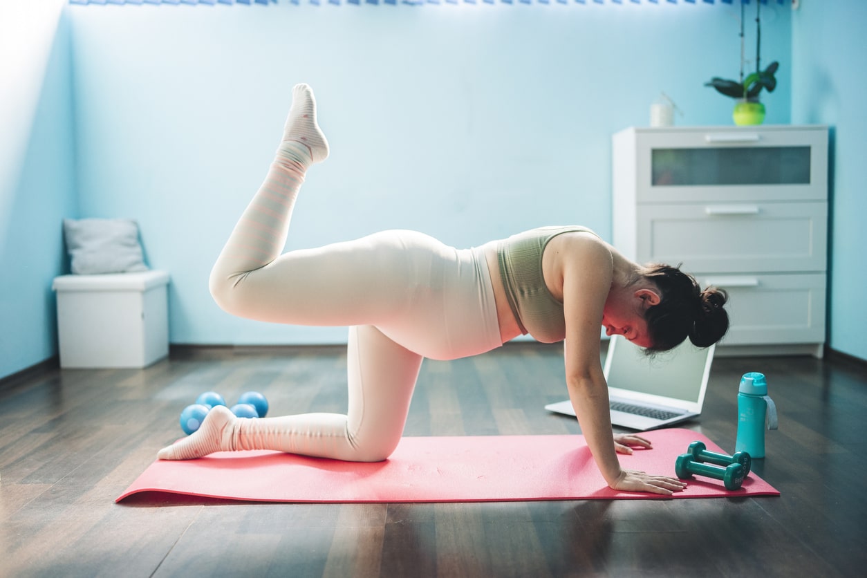 Pregnant woman takes a break from sitting at desk working to do some exercises and stretches. 